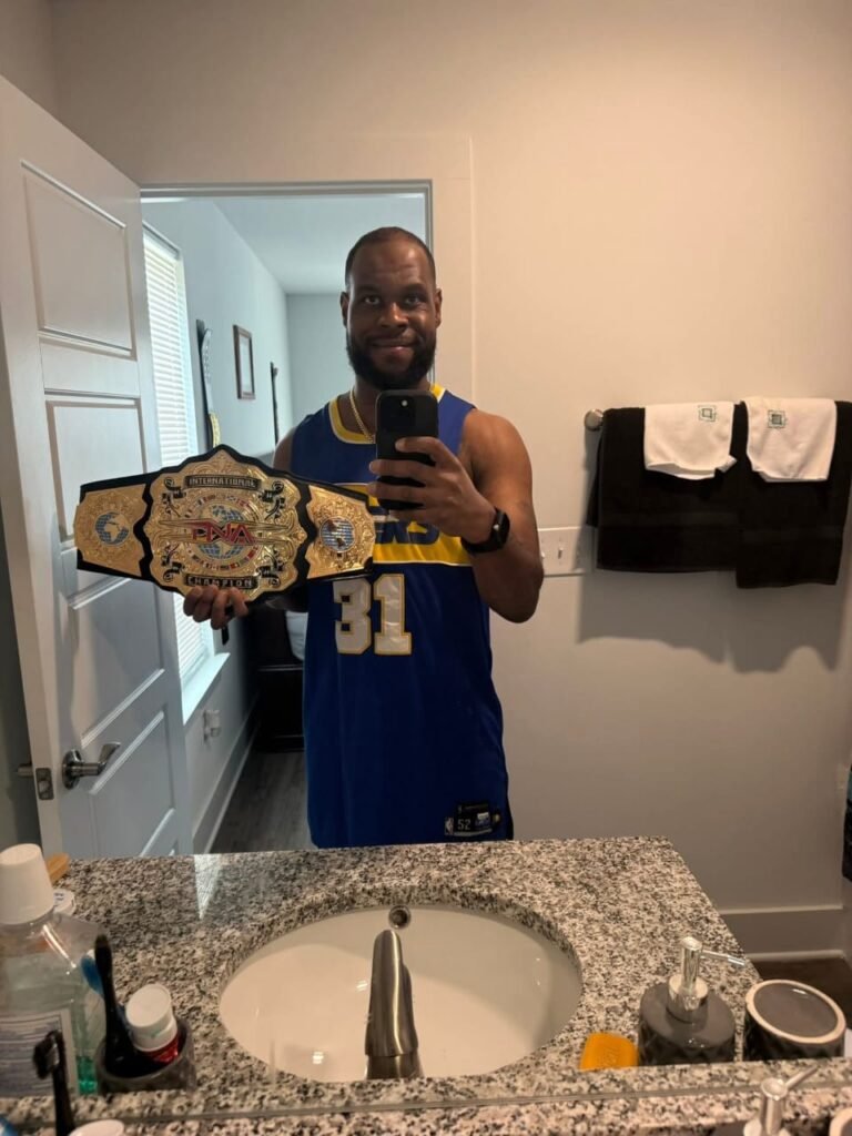 The black man hanging the wrestling championship with his shoulder